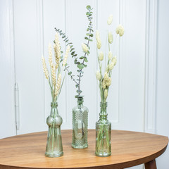 Interieurtrend Minimalismus, dekorative Glasvasen mit Eukalyptus und getrockneten Gräsern und...