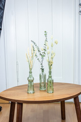 Interieurtrend Minimalismus, dekorative Glasvasen mit Eukalyptus und getrockneten Gräsern und Blumen