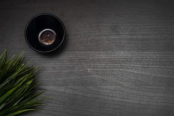 cup of tea on a dark wooden table with decorating grass
