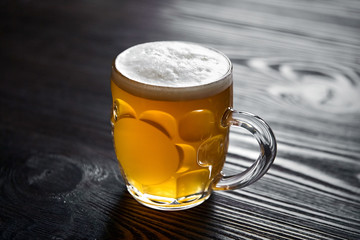 Mug of unfiltered light wheat beer on brown wooden table