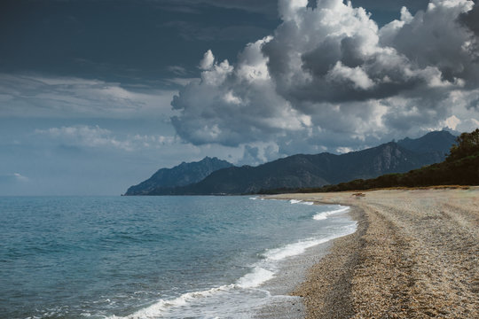Vista sul mare con montagne e nuvole nella spiaggia Sa Marina a Barisardo (Sardegna)