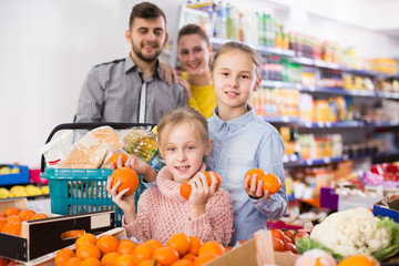Fototapeta premium Glad little girl choosing fresh mandarins