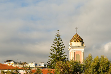 Obraz premium Top of the bell tower of the little church of Saint Joseph in the coastal town of Arma di Taggia against cloudy sky, province of Imperia, Riviera of Flowers, Liguria, Italy