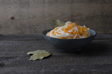 fermented white cabbage on a gray plate on a wooden background.