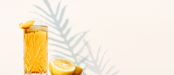 Banner with a glass of Ice Tea isolated against a white wall with plant shadows