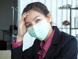 Asian business woman is wearing mask for protection from coronvirus or covid-19 or pm 2.5.Woman with flu working in the office.