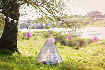 Decoration for children's photography with teepee and tree at sunset. © Cubodeluz