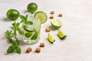 Cooling drink with ice, lime and mint. Slices of brown sugar, mint leaves, lime fruits.