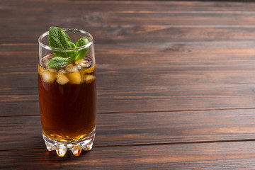 Cooling summer tea with ice and mint. Dark wood background. Copy space.