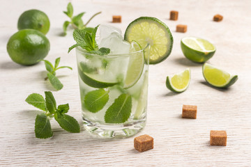 Cooling drink with ice, lime and mint. Slices of brown sugar, mint leaves, lime fruits.