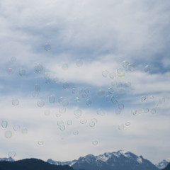 Many soap bubbles in front of cloudy sky and mountain chain