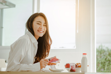 Young woman asia wake up refreshed in the morning and relaxing eat coffee, cornflakes, bread and apple for breakfast at house on holiday. Asian, asia, relax, breakfast, refresh, lifestyle concept.