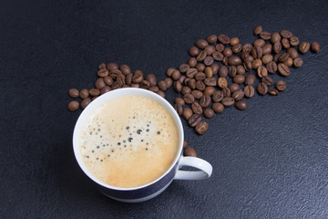 cup of espresso and cofee seeds on black background close up