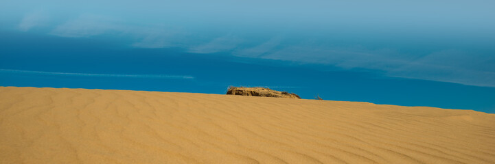 Sand dunes and sand waves and blue sky with clouds.
