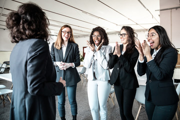 Obraz premium Mature colleague talking to happy younger colleagues. Professional business team listening mentor, applauding and rejoicing. Business concept