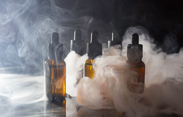 Glass bottles with pipettes and VAPE liquid. Thick vapor from Smoking an electronic cigarette.