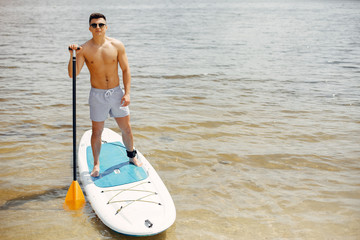 Handsome man with a sup. Surfer on a water