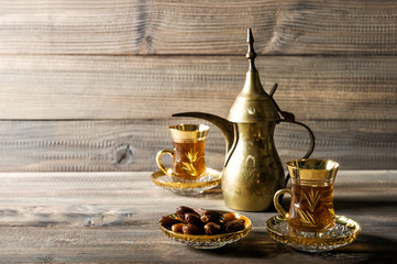 Fototapeta na wymiar Tea pot glasses golden oriental decoration wooden background