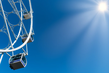 The Ferris wheel and the blue sky in the background. People enjoy the attraction