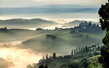Sunrise over misty landscape of Italy. Early morning over rural area with gardens, farms, trees,...