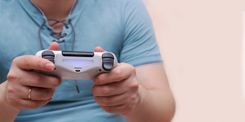 A young man holds a game controller and plays video games