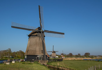 Fototapeta na wymiar Krajobraz Holandii, wiatraki nad kanałem wodnym.