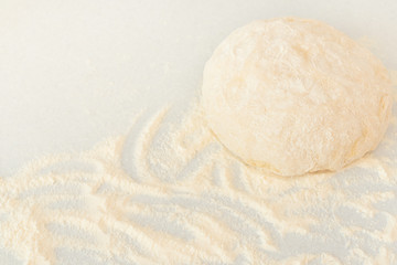 Fresh raw dough ball covered with wheat flour on grey background with dusting of flour. Home cooking, stay home, baking concept. Copy space for text.