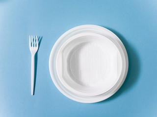 Plastic dishes, disposable tableware, plates, glasses, spoons, forks on a blue background. Caring for the environment. The problem is recycling. Reuse, safe planet, environmental concept. Trash.