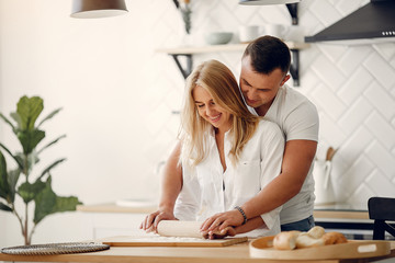 Fototapeta premium Couple in a kitchen. Blonde in a white shirt. Woman with her husband