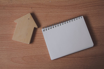 Blank notebook with miniature house on wood table. copy space.