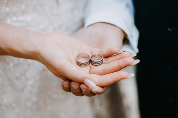 Two wedding rings lie on the hands of the newlyweds. Wedding ceremony.