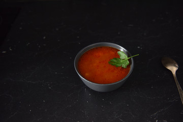 fresh tomato soup with greens on a black background