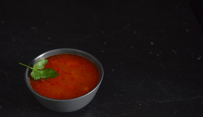 fresh tomato soup with greens on a black background
