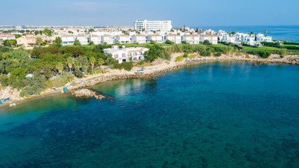 Aerial bird's eye view of Sirena beach in Protaras, Paralimni, Famagusta, Cyprus. The famous Sirina bay tourist attraction with sunbeds, golden sand, restaurant, people swimming in the sea from above.
