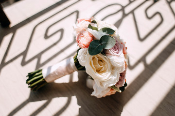 A wedding bouquet of roses and eucalyptus lies on a wooden background. Preparing for the wedding day. Morning of the bride