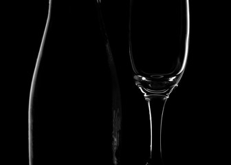 White silhouette of a bottle and glass Cup isolated on a black background. Smooth lines and shapes. Concept.