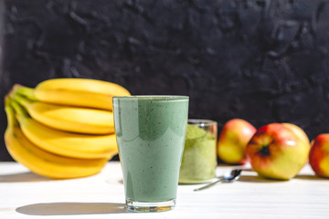 The concept of food and drink, diet and nutrition. Healthy green vegan smoothie with banana, spirulina and ripe apple for summer detoxification
