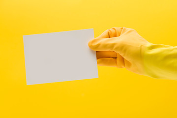 hand in a yellow cleaning glove holing a blank white card