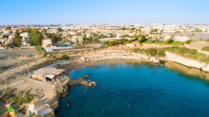 Fototapeta premium Aerial bird's eye view of Kapparis (fireman's) beach in Protaras, Paralimni, Famagusta, Cyprus. Tourist attraction golden sand Kaparis bay with boats, sunbeds, sea restaurants, water sports from above