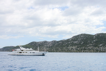 Fototapeta na wymiar White luxury yacht in the sea on the background of rocks