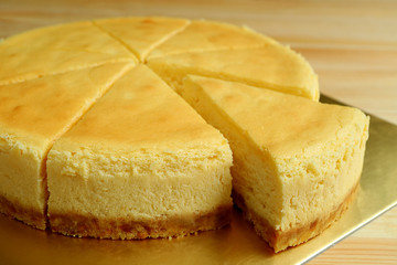Closeup a slice of creamy yellow plain baked cheesecake cut from the whole cake