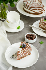 No baked zebra marble cheesecake with vanilla and chocolate layers on a white plate on a concrete background. Vertical orientation. Copy space.