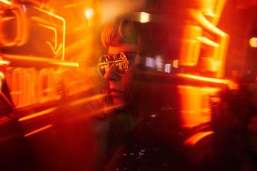 Woman with fringe wearing sunglasses with orange yellow red neon lights