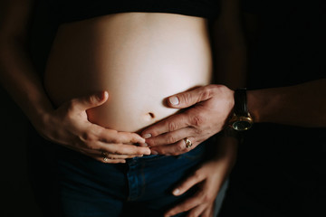 Hands of a man and a woman hug a pregnant belly. Young parents waiting for the baby