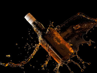 Whiskey bottle splash on black background
