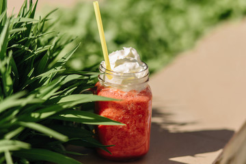 Fruit smoothie in a glass jar on a background of lush green grass. Summer cocktail
