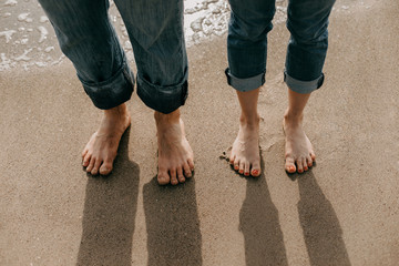 Bare feet of lovers on the seashore. Close-up on top
