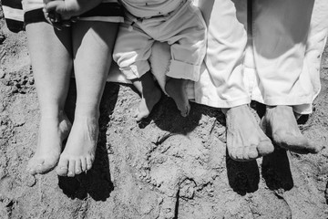 Feet of the family on the sand by the sea. Holidays with the whole family on the beach in the summer. Close-up on top