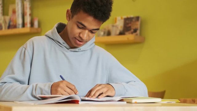 Handsome concentrated young african guy student studying doing homework.