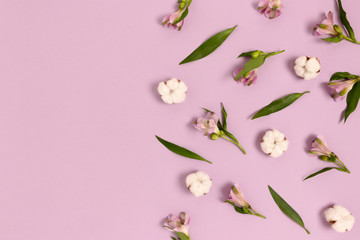 Frame made of green leaves, cotton, alstroemeria flowers on a purple pastel background. Spring concept with copy space.